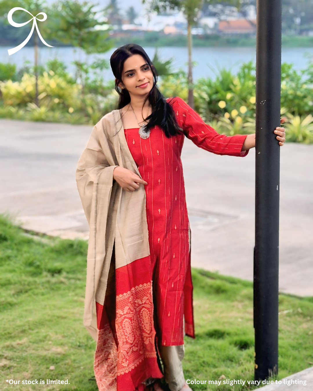 Woman in a red traditional outfit standing outdoors by a lake
